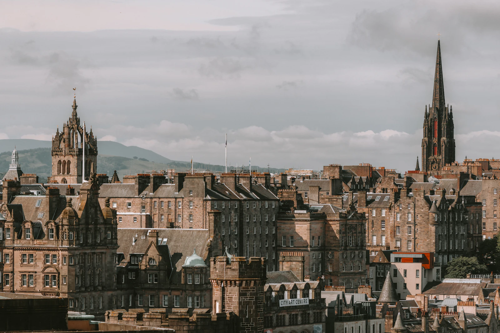 Historic stone buildings, rooftops and church spires beneath a cloudy sky